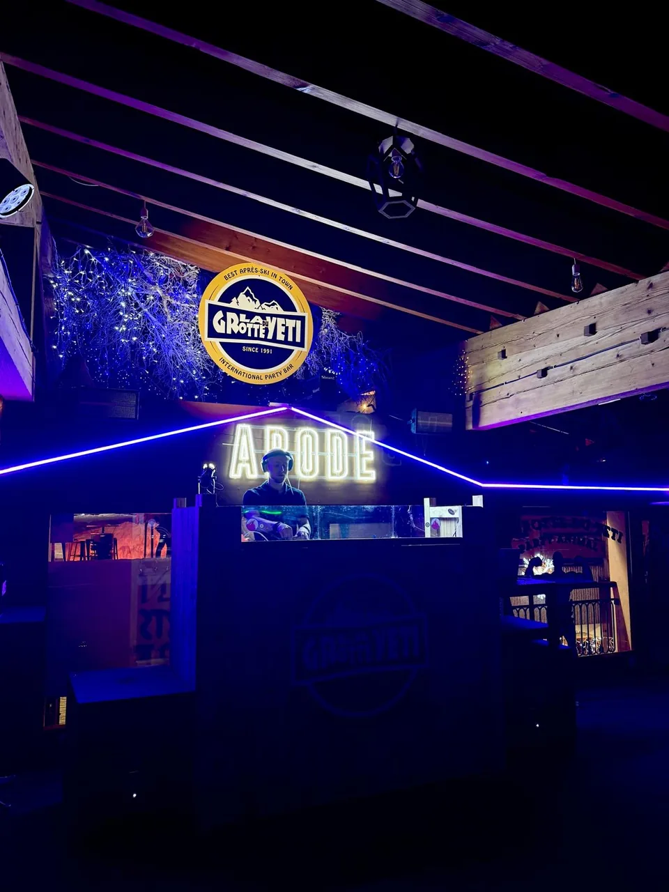 NATUS in a DJ booth surrounded by blue lighting and wooden beams