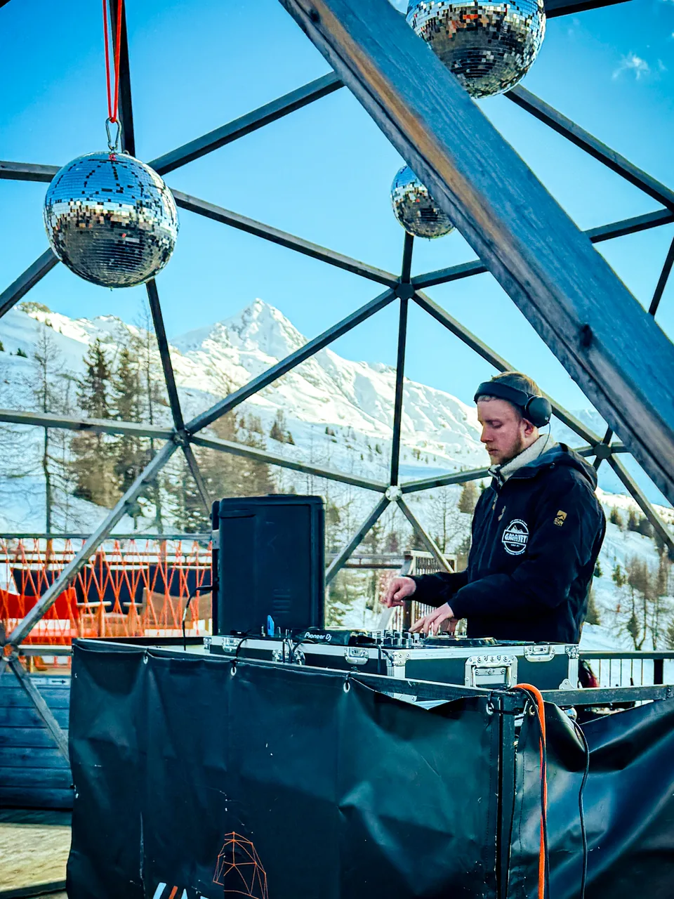 Side view of NATUS at the decks in a glass dome with snowy mountains outside
